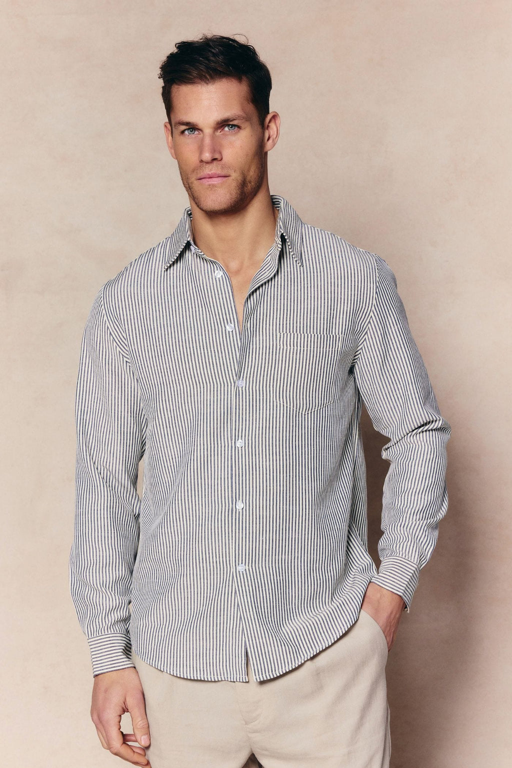 Man wearing an Abilo Ecru/Navy striped shirt with an open collar, chest pocket, and light trousers.