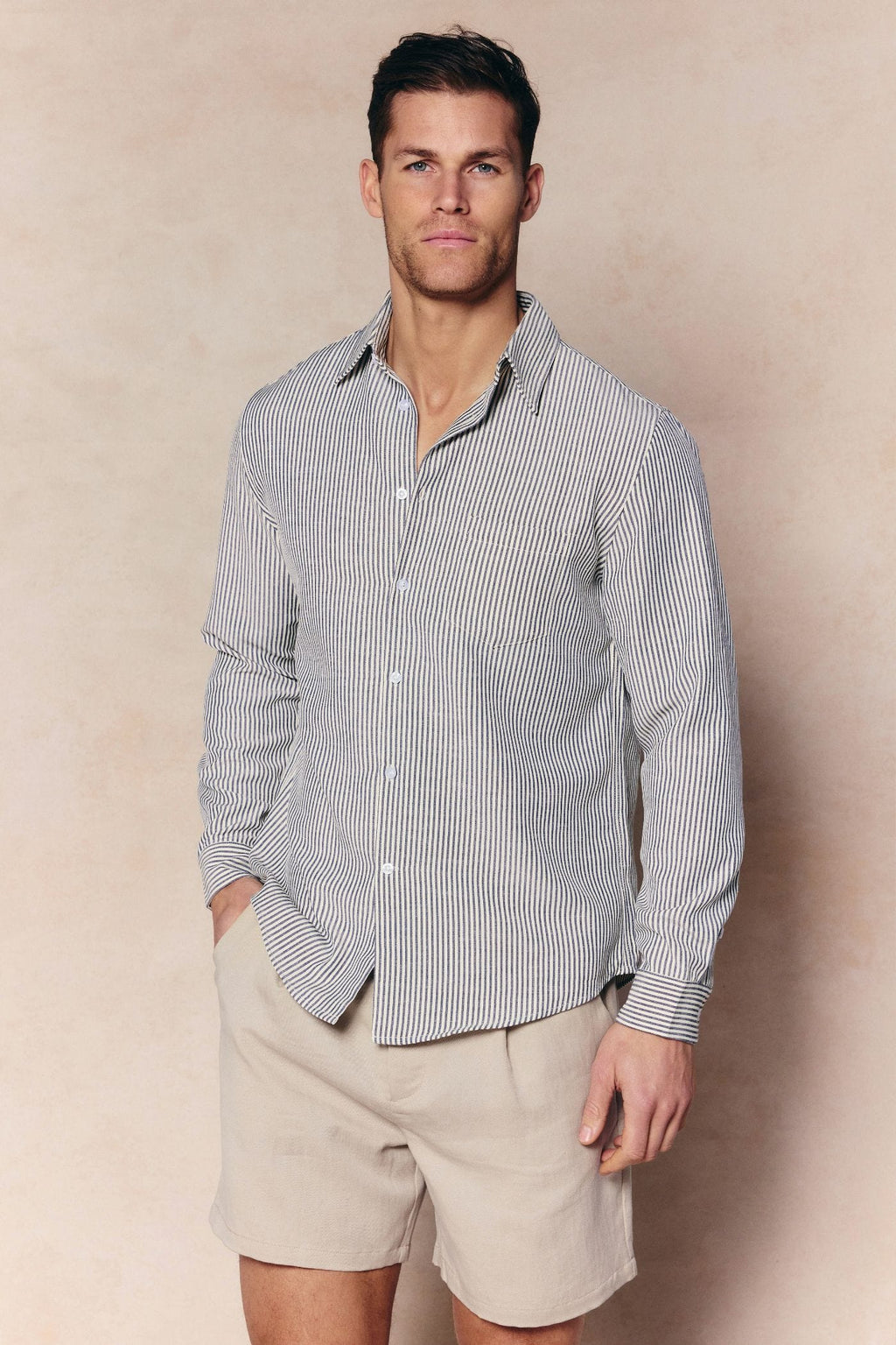 Man wearing an Abilo Ecru/Navy striped shirt with an open collar and beige shorts.