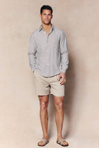 Man wearing an ecru/navy striped Abilo shirt with an open collar, chest pocket, and tailored fit, paired with beige shorts.