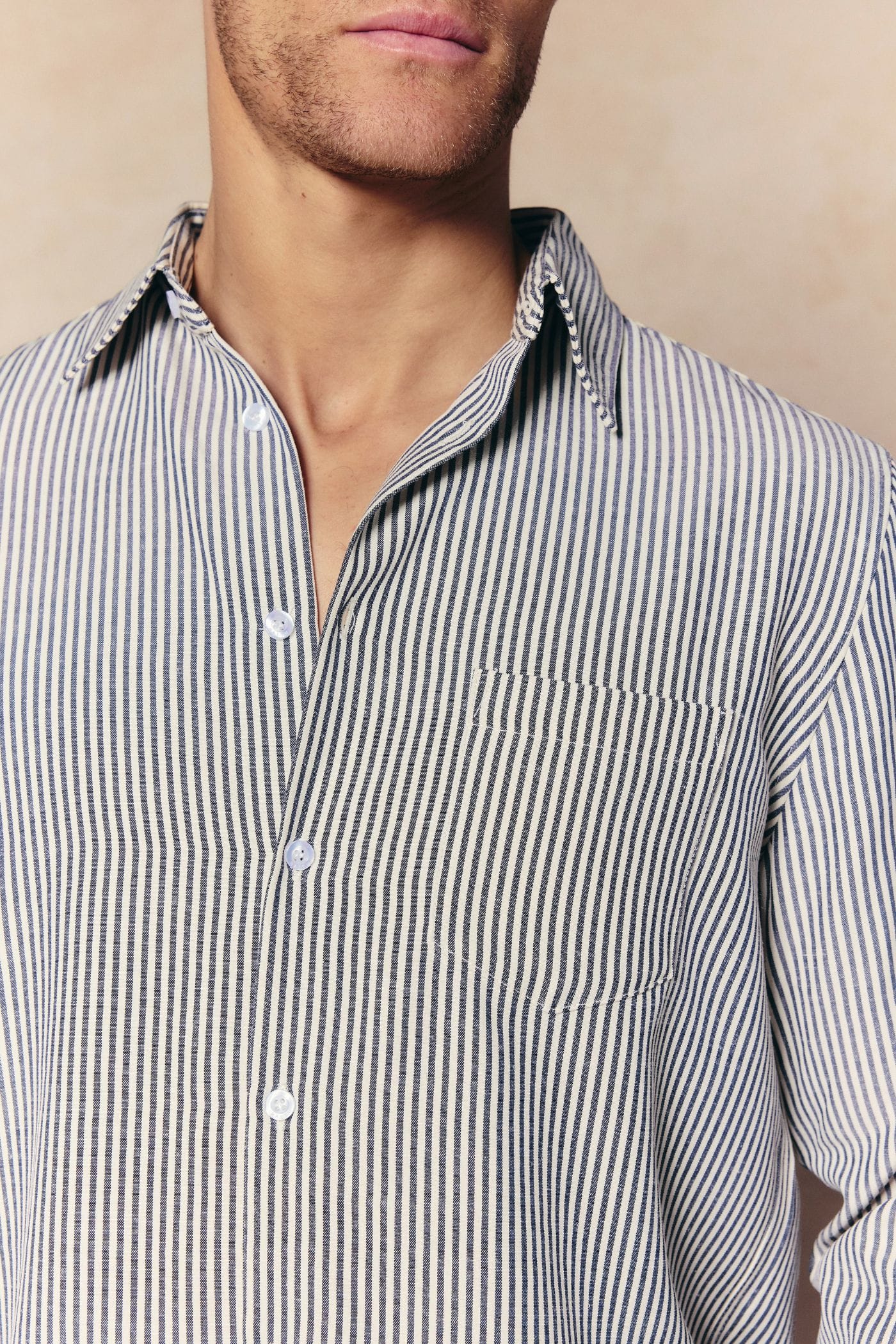 Man wearing an Abilo Ecru/Navy striped shirt with an open collar, chest pocket, and subtle vertical stripes.
