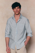 Man in Abilo Khaki/Ecru striped shirt, tailored fit, open collar, chest pocket, paired with light trousers.