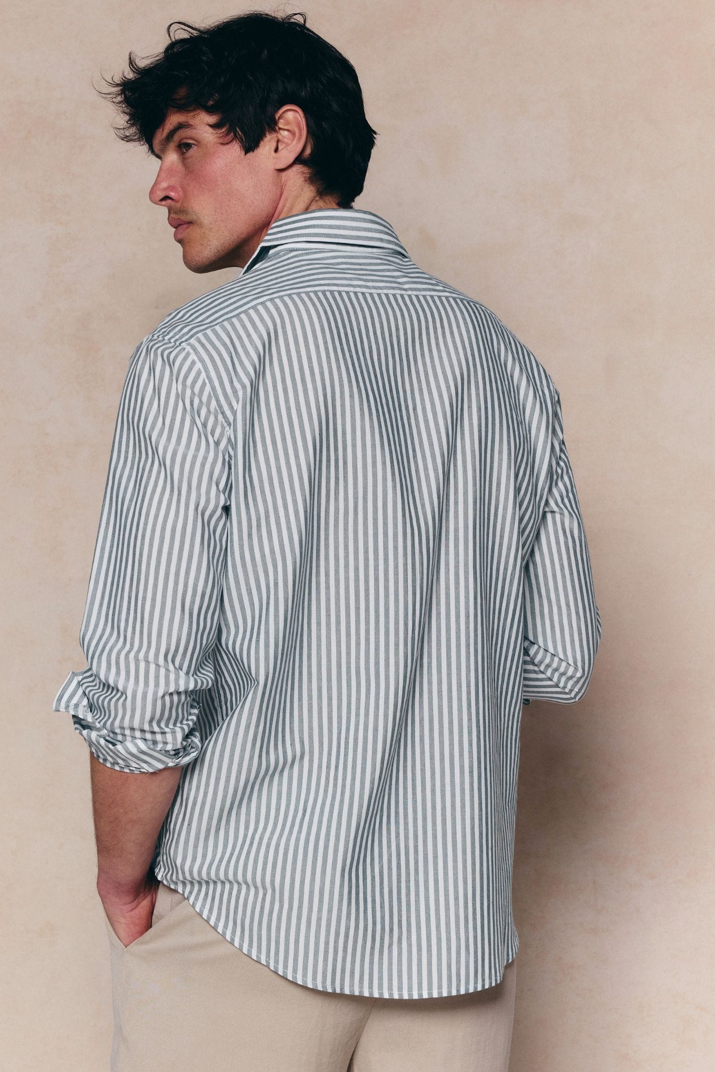Man wearing Abilo Striped Shirt in khaki/ecru, tailored fit, with rolled sleeves and open collar.