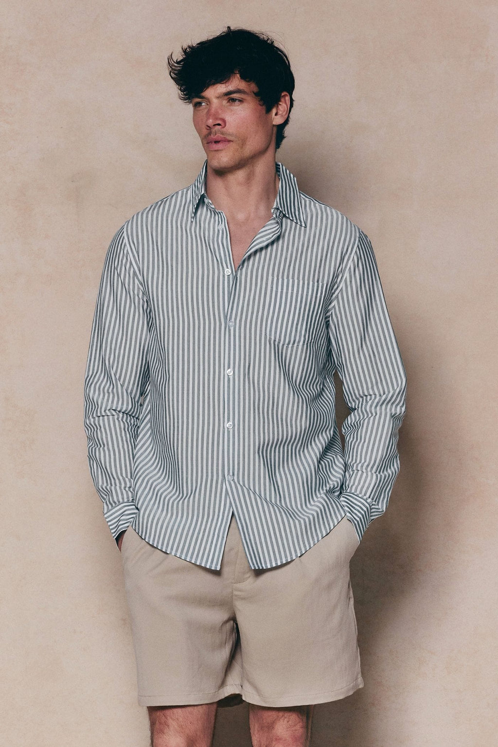 Man in tailored Abilo Khaki/Ecru striped shirt with open collar and chest pocket, paired with beige shorts.