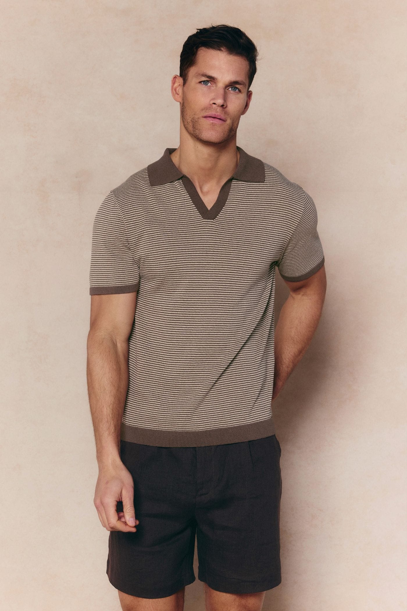 Man in brown/beige striped linen polo with open collar and contrast trim.