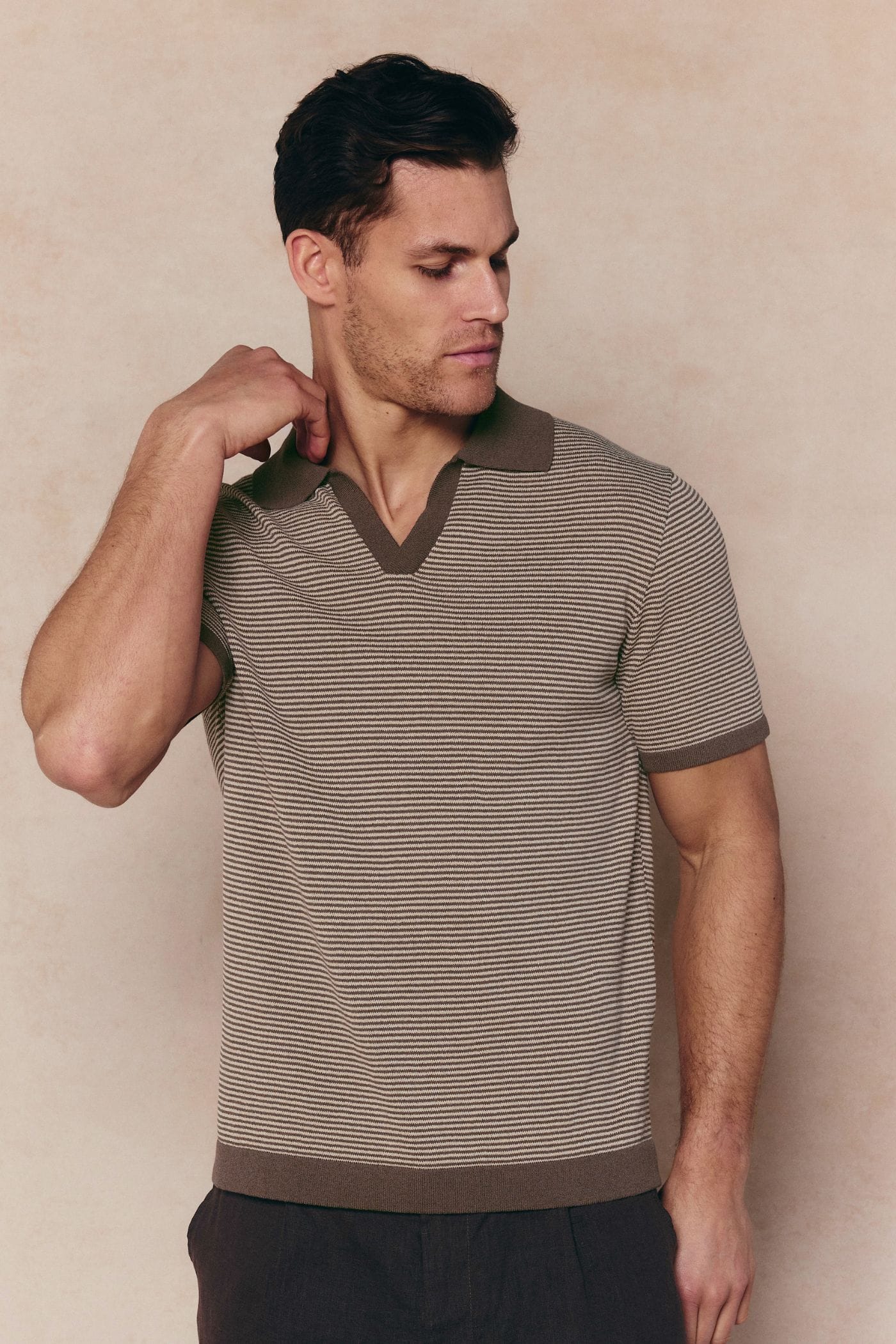 Man in Antonio brown/beige striped linen polo with open collar and contrast trim.