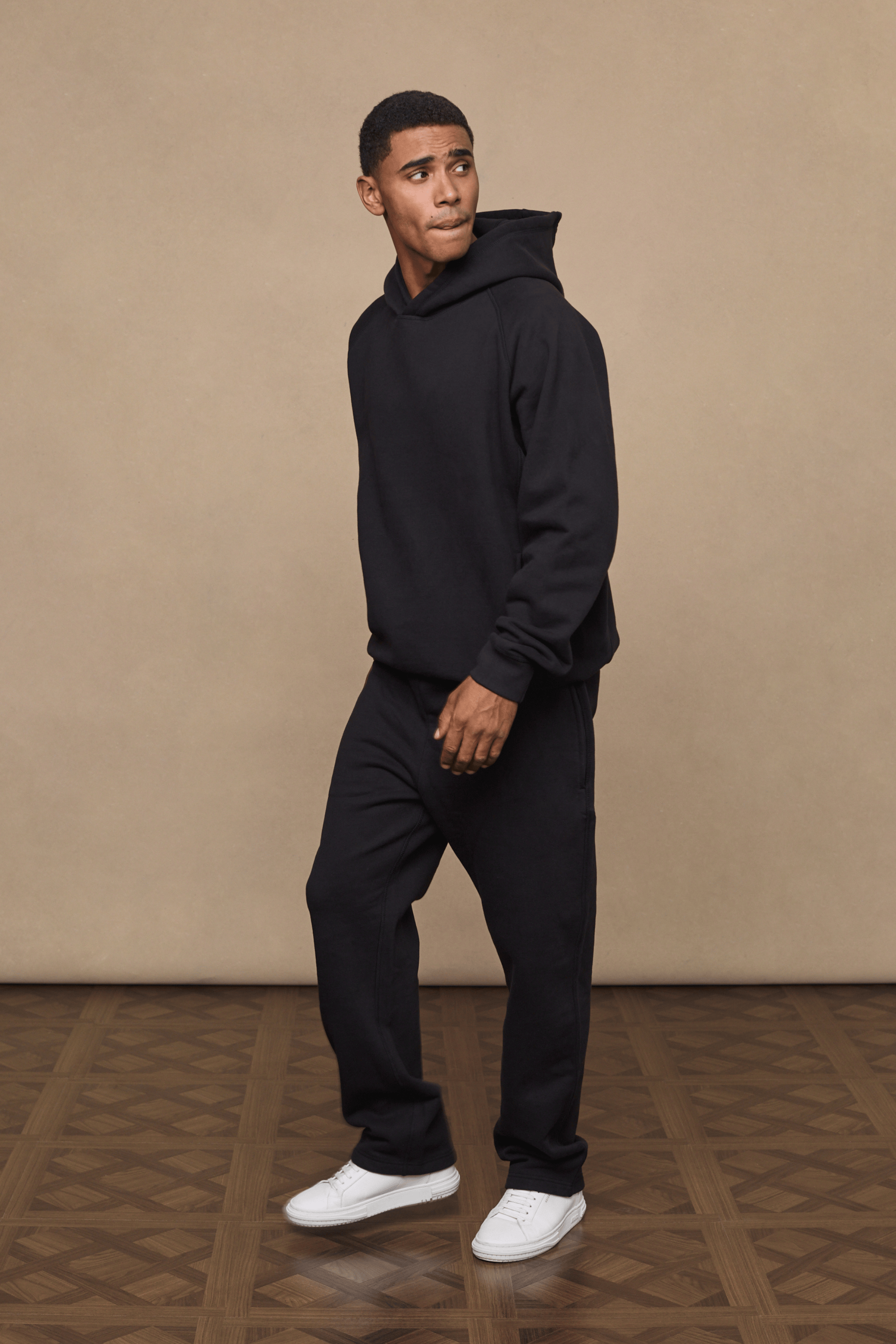 Man wearing black Axel straight leg joggers and matching hoodie with white sneakers.