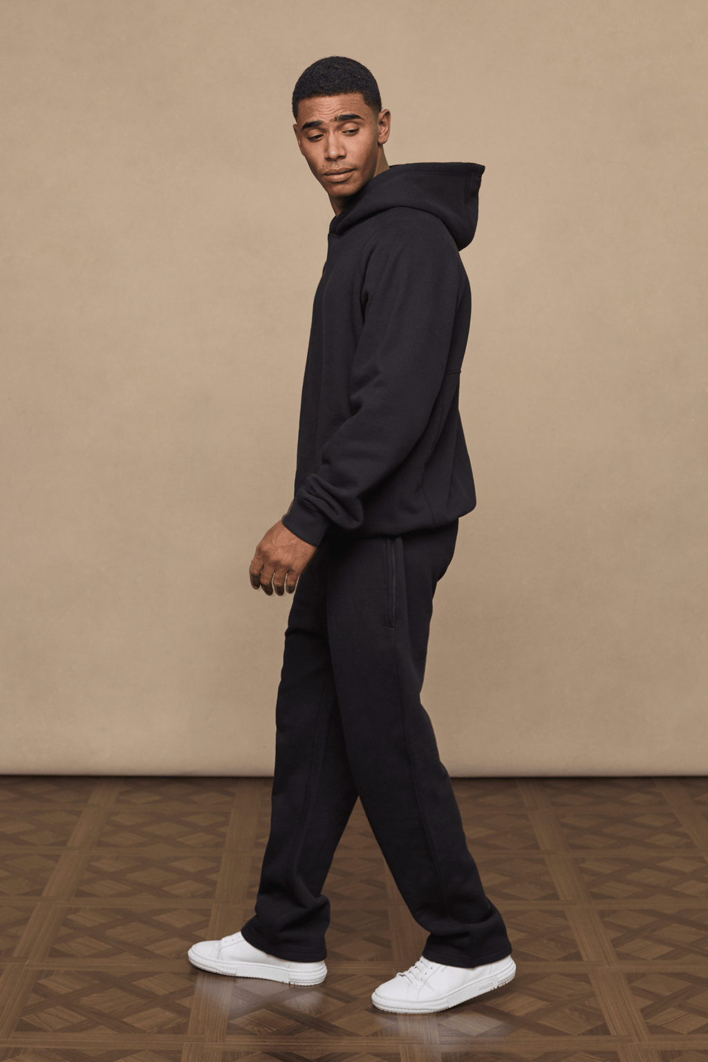 Man wearing black Axel straight leg joggers and matching hoodie with white sneakers.