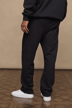 Black Axel straight leg joggers made from heavyweight cotton-polyester blend, paired with a matching hoodie and white sneakers.
