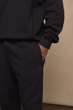 Black Axel straight leg jogger and matching hoodie, crafted from heavyweight fleece, with a hand in the side pocket.