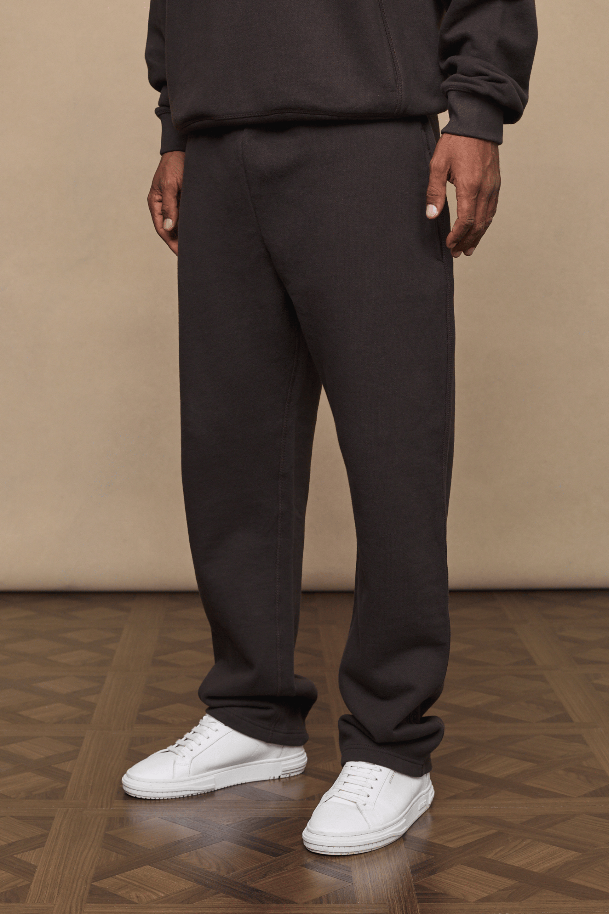 Dark brown Axel straight leg jogger and matching hoodie on a person, paired with white sneakers.