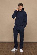 Man wearing a dark navy Axel Straight Leg Jogger and matching hoodie, crafted from heavyweight fleece.