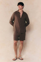 Man wearing a relaxed fit brown linen classic collar shirt and matching shorts with sandals.