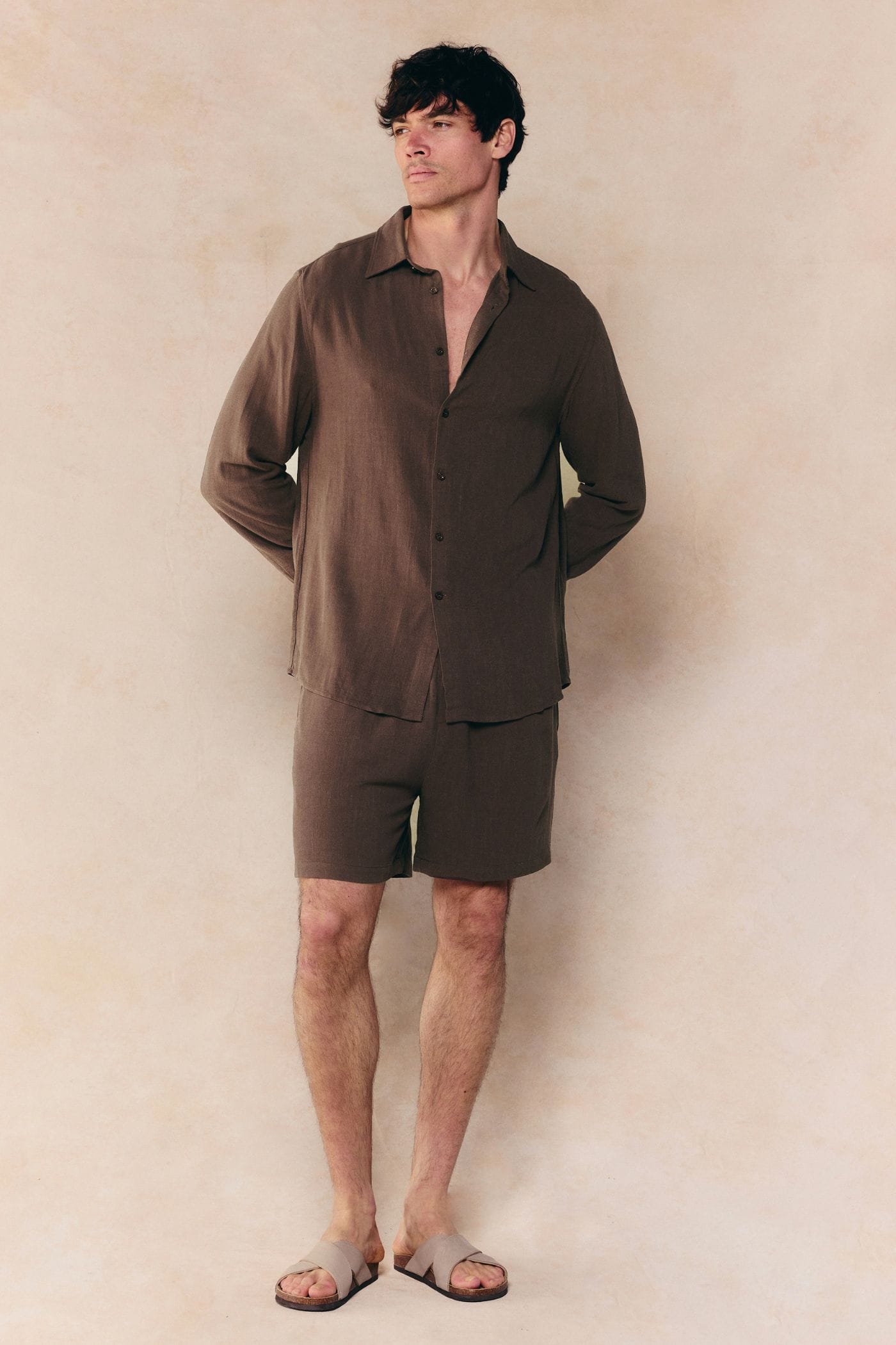 Man wearing a relaxed fit brown linen classic collar shirt and matching shorts with sandals.