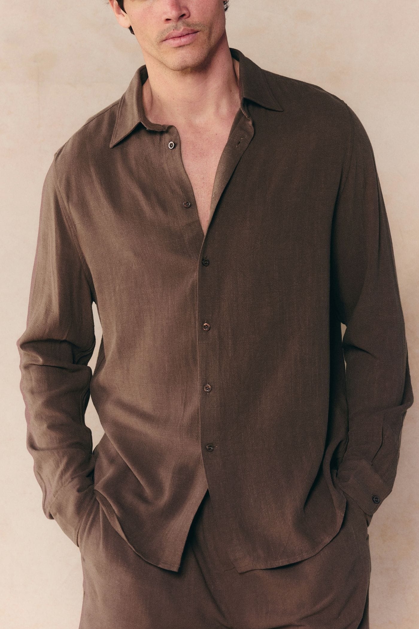 Man wearing a brown Cami Linen Classic Collar Shirt with long sleeves, relaxed fit, and open top button.