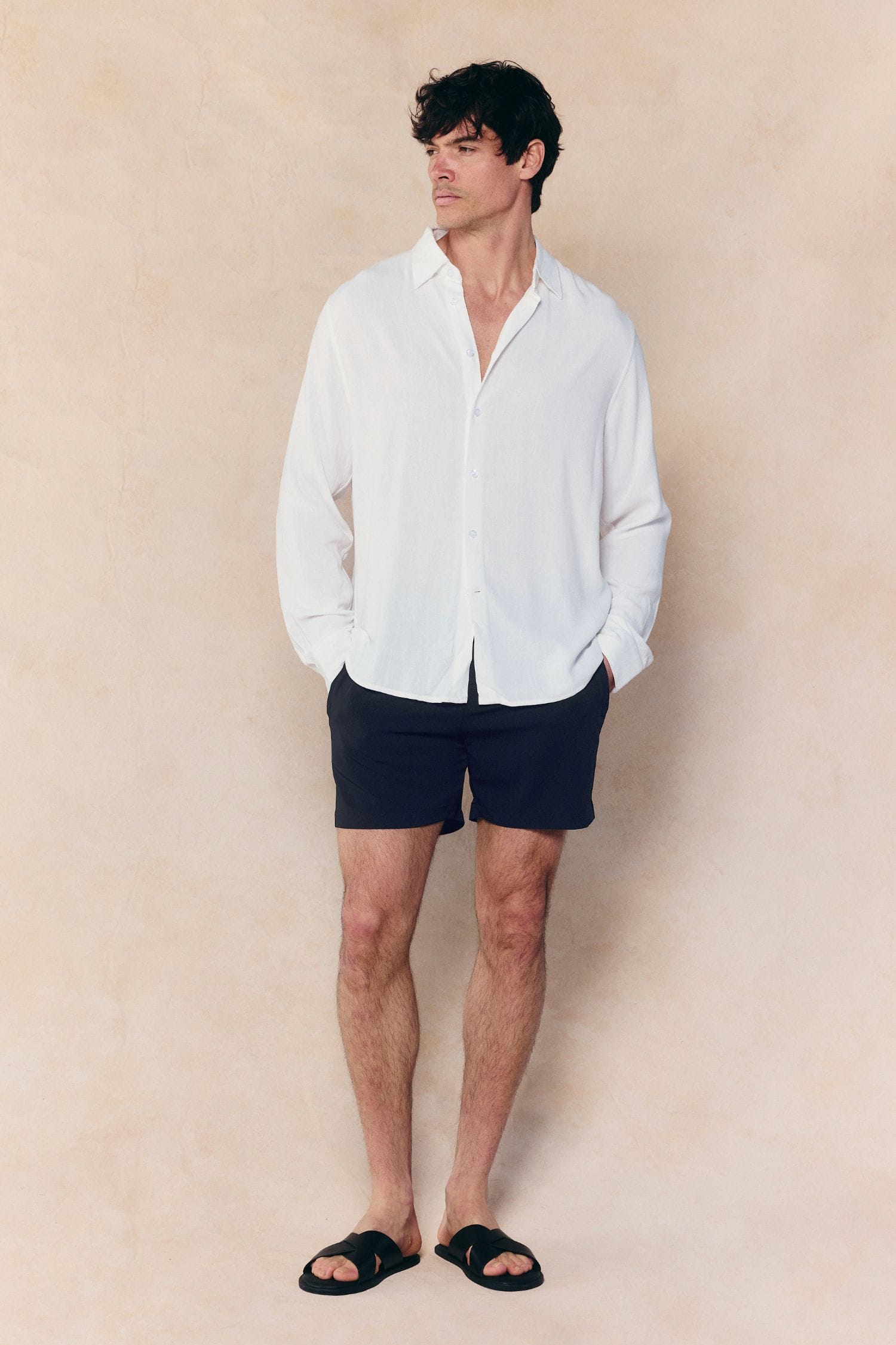 Man in ecru Cami Linen Classic Collar Shirt and black shorts.