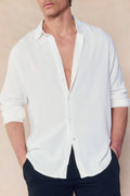 Man wearing an ecru Cami Linen Classic Collar Shirt with rolled sleeves and black pants.