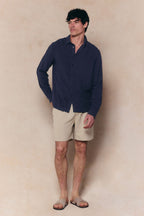 Man wearing a navy Cami Linen Classic Collar Shirt and beige shorts.