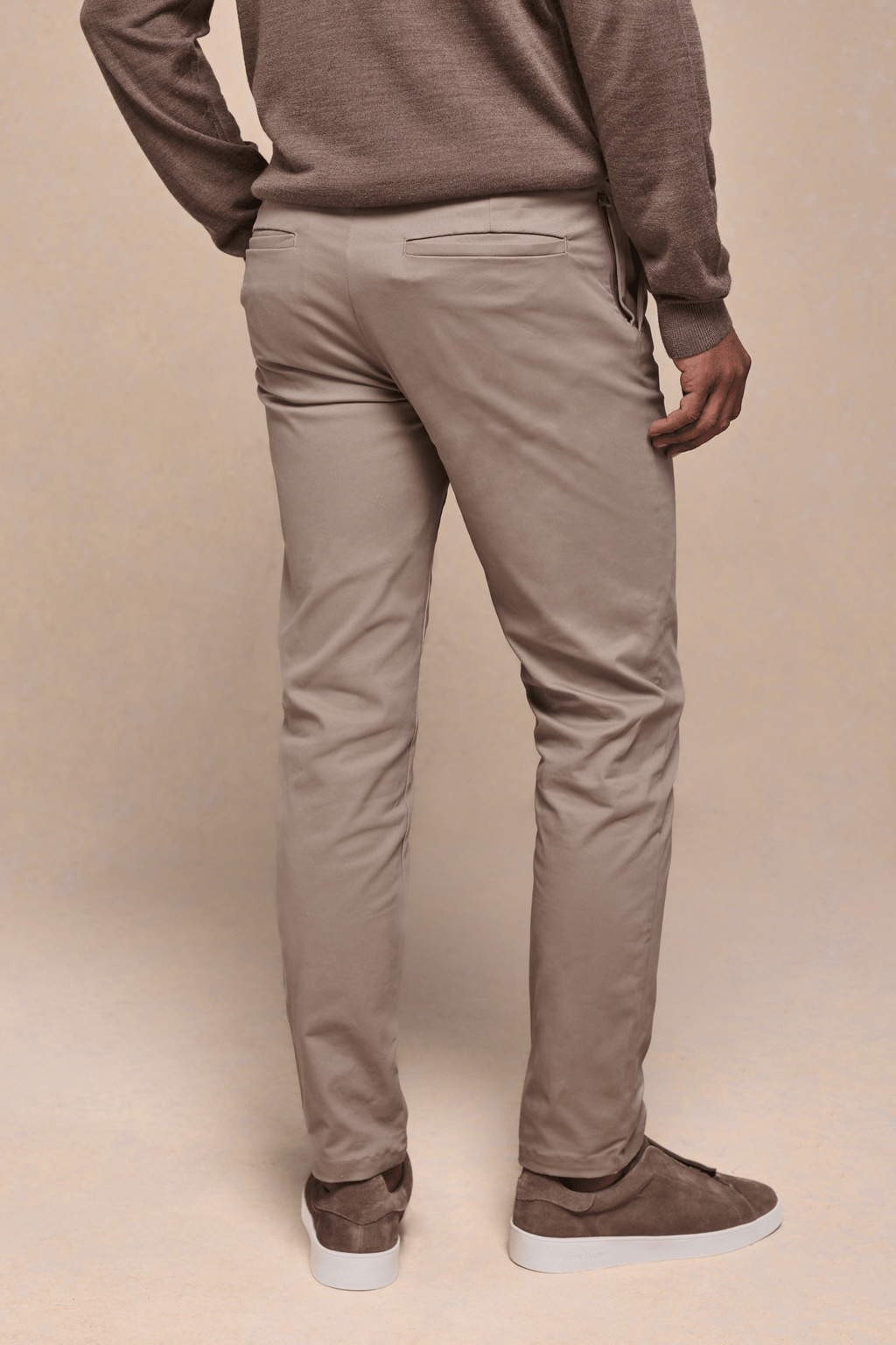 Man wearing beige Elliot Easy Chino trousers with a modern silhouette and brown suede sneakers.