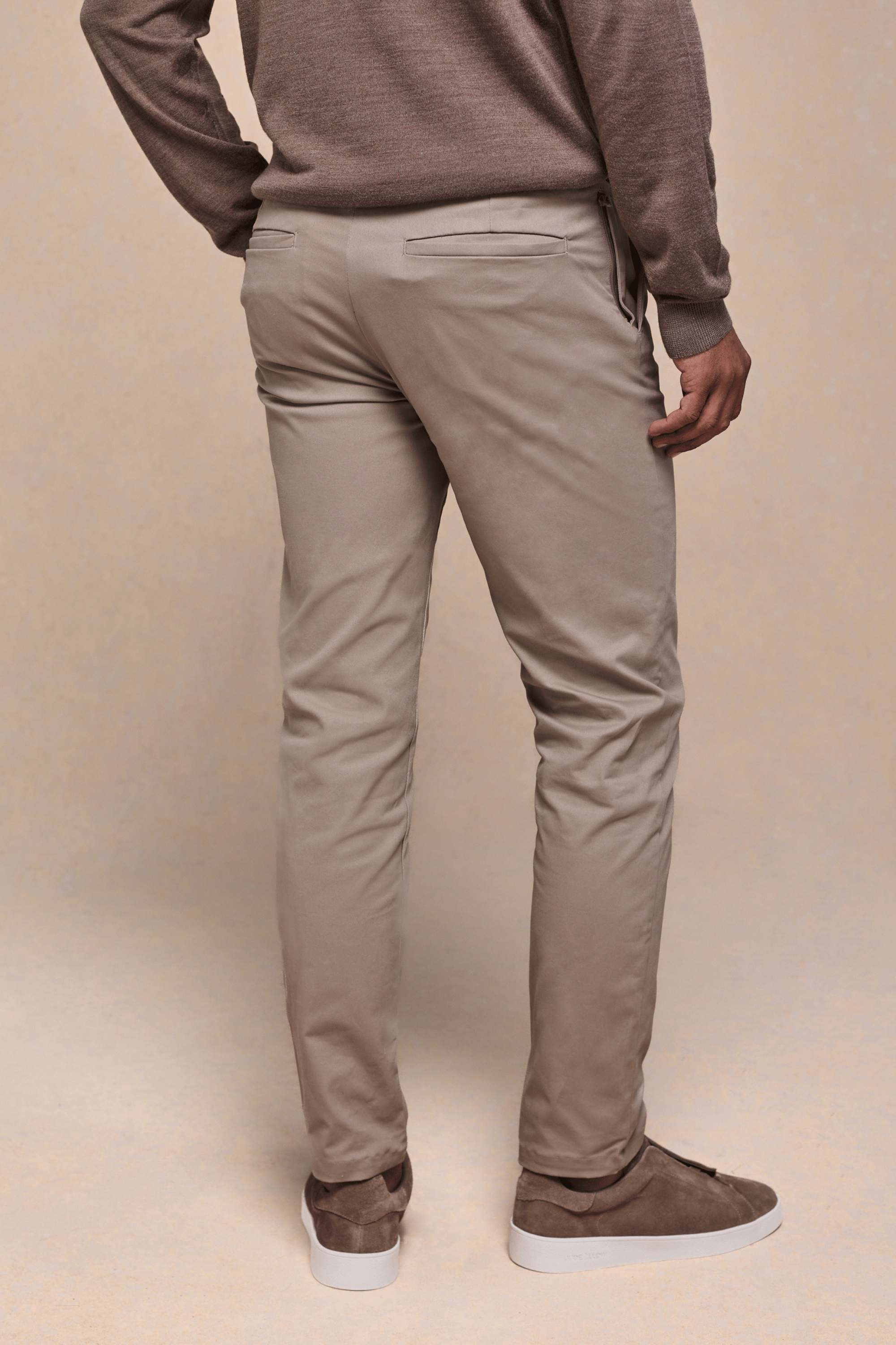 Man wearing beige Elliot Easy Chino trousers with a modern silhouette and brown suede sneakers.