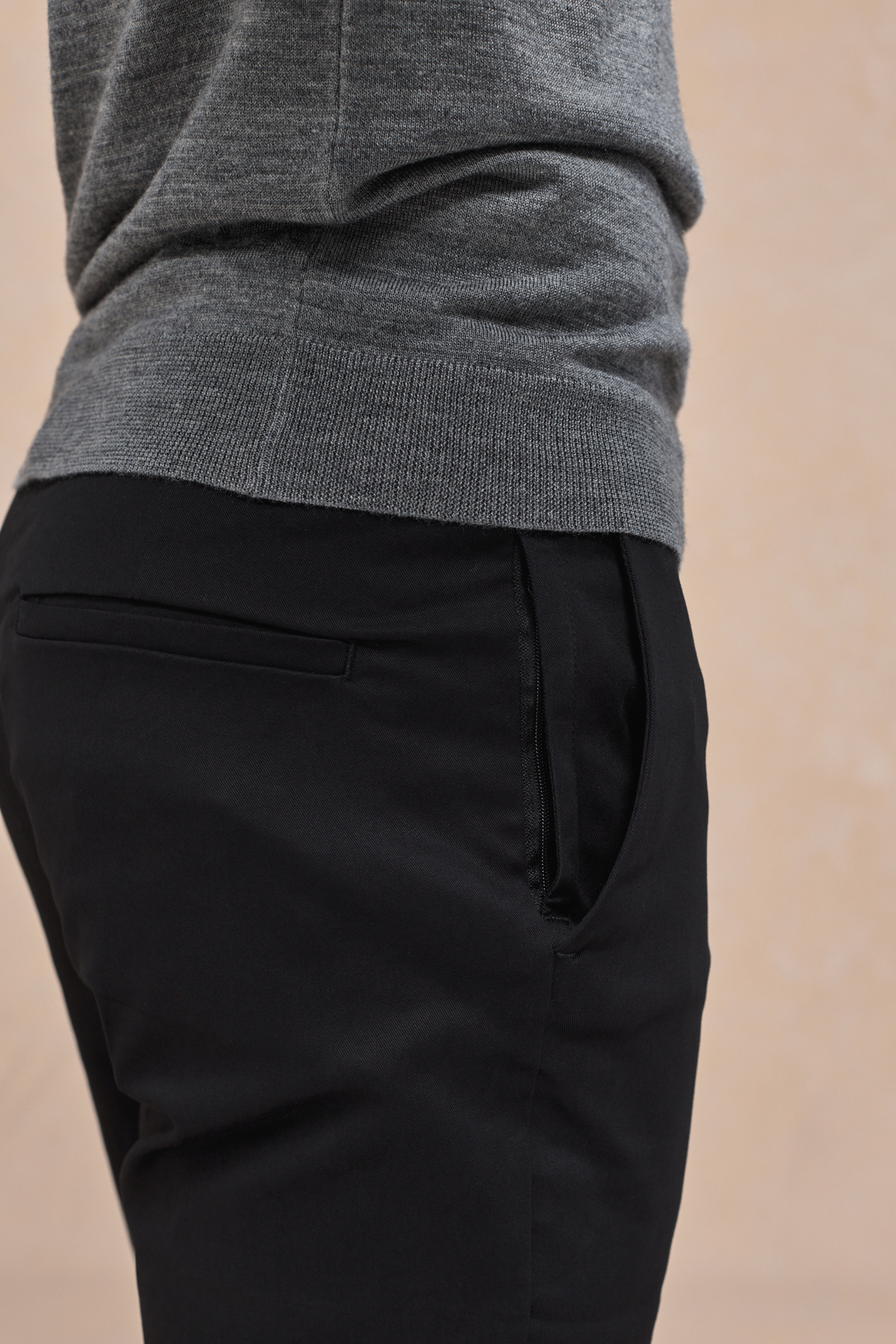 Black Elliot Easy Chino pants with side entry pockets, worn by a person in a grey sweater.