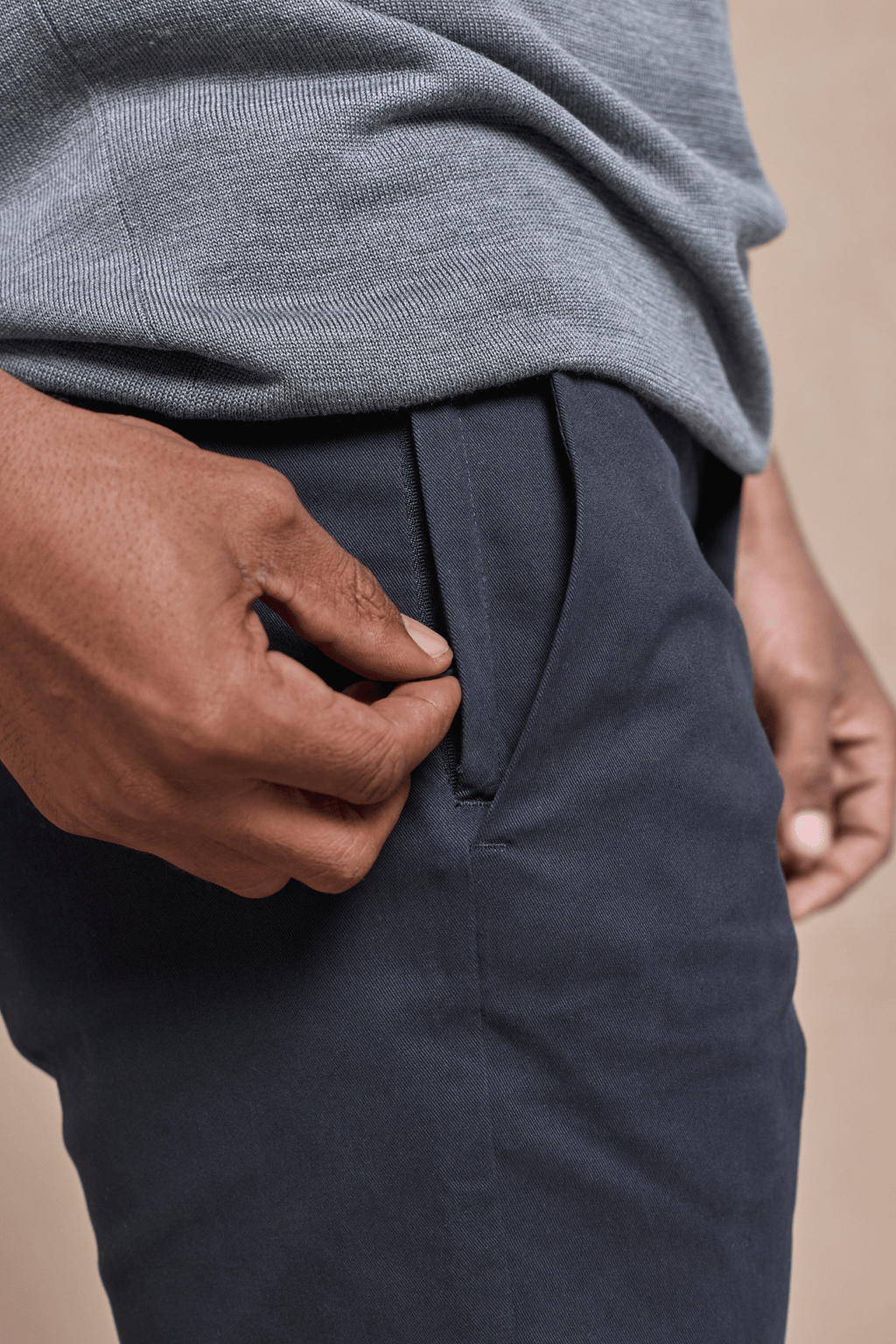 Close-up of a hand opening the concealed zip pocket on dark navy Elliot Easy Chino pants.