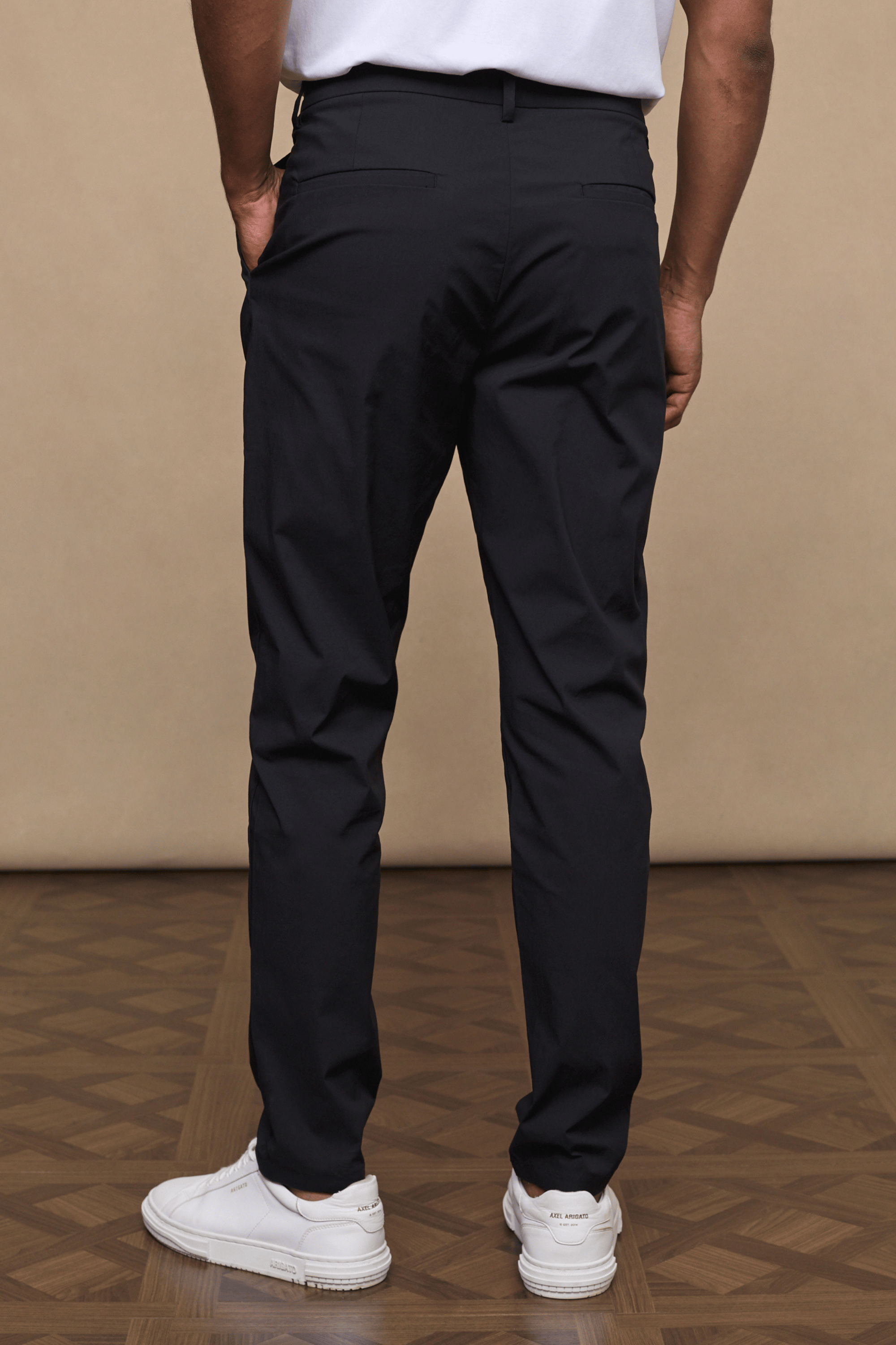 Man wearing black Enzo Hybrid Trousers with belt loops, side pockets, and white sneakers.