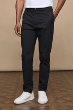 Man wearing black Enzo Hybrid Trousers with branded popper buttons, belt loops, and side pockets.