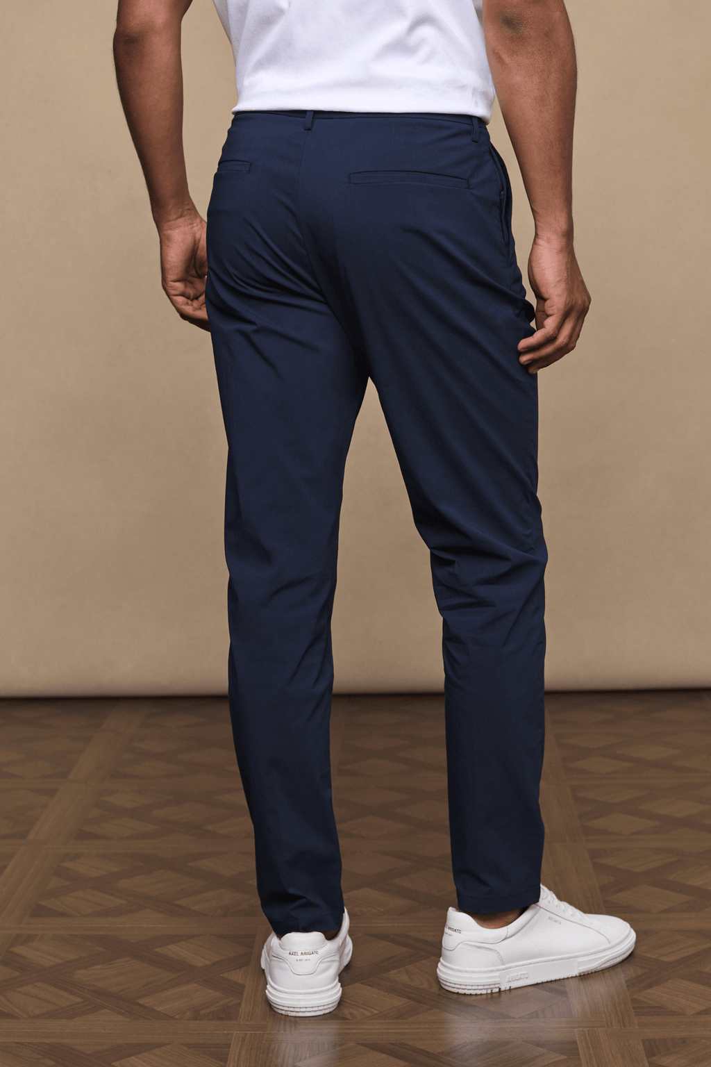 Man from behind wearing dark navy Enzo Hybrid Trousers with a clean, modern silhouette and white sneakers.