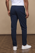 Man from behind wearing dark navy Enzo Hybrid Trousers with a clean, modern silhouette and white sneakers.