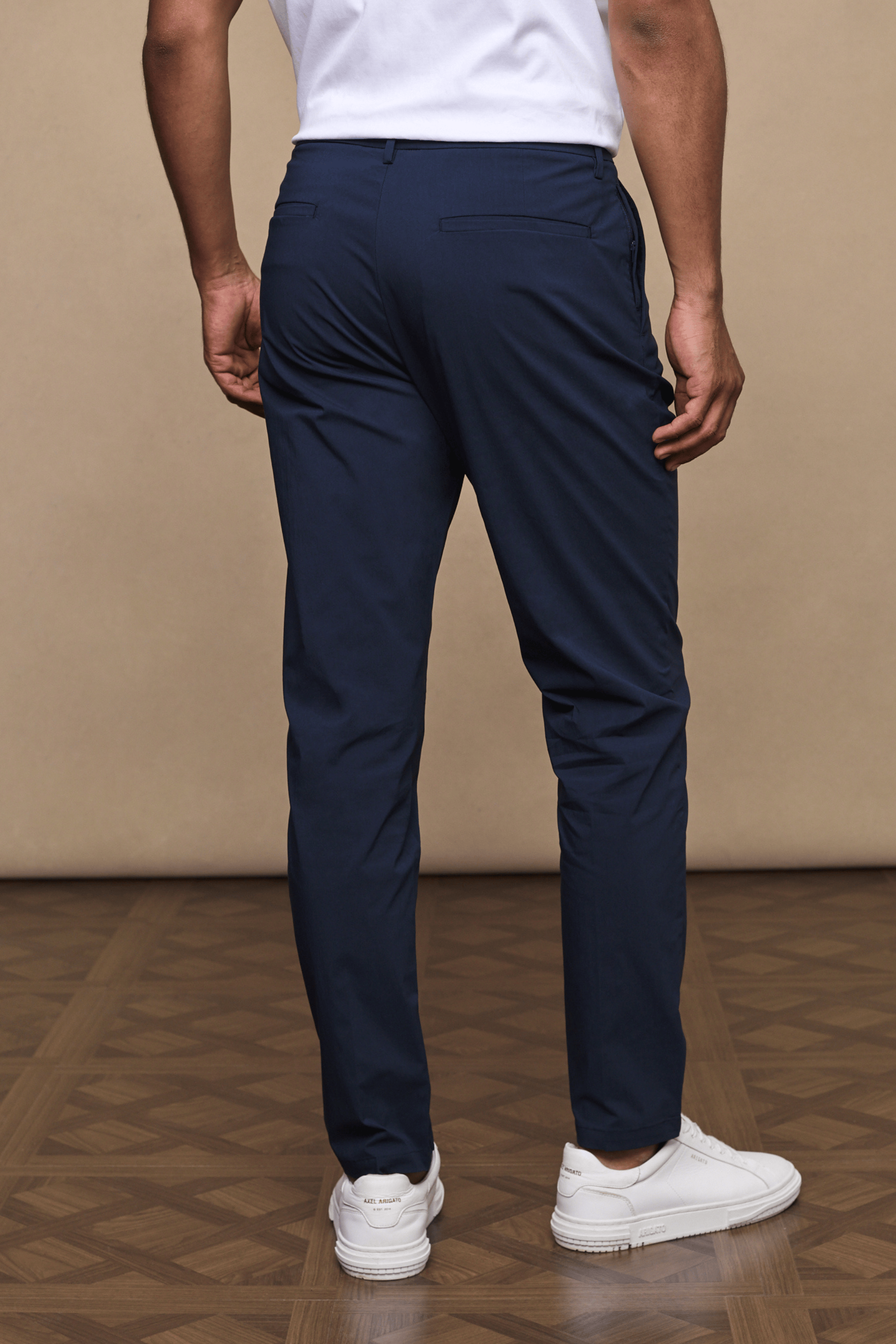 Man from behind wearing dark navy Enzo Hybrid Trousers with a clean, modern silhouette and white sneakers.