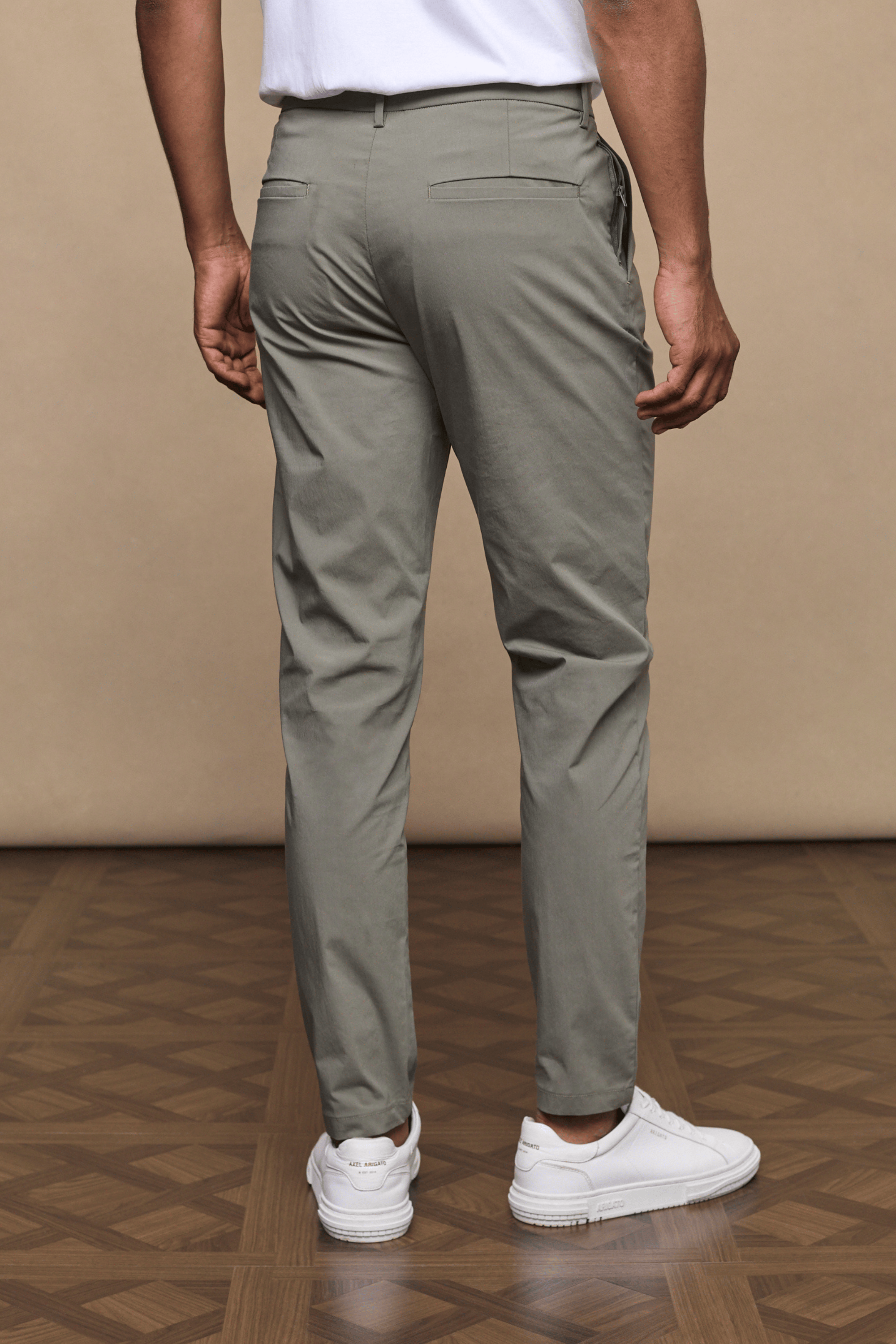 Man from behind wearing dark olive Enzo Hybrid Trousers, 4-way stretch fabric, with white sneakers.