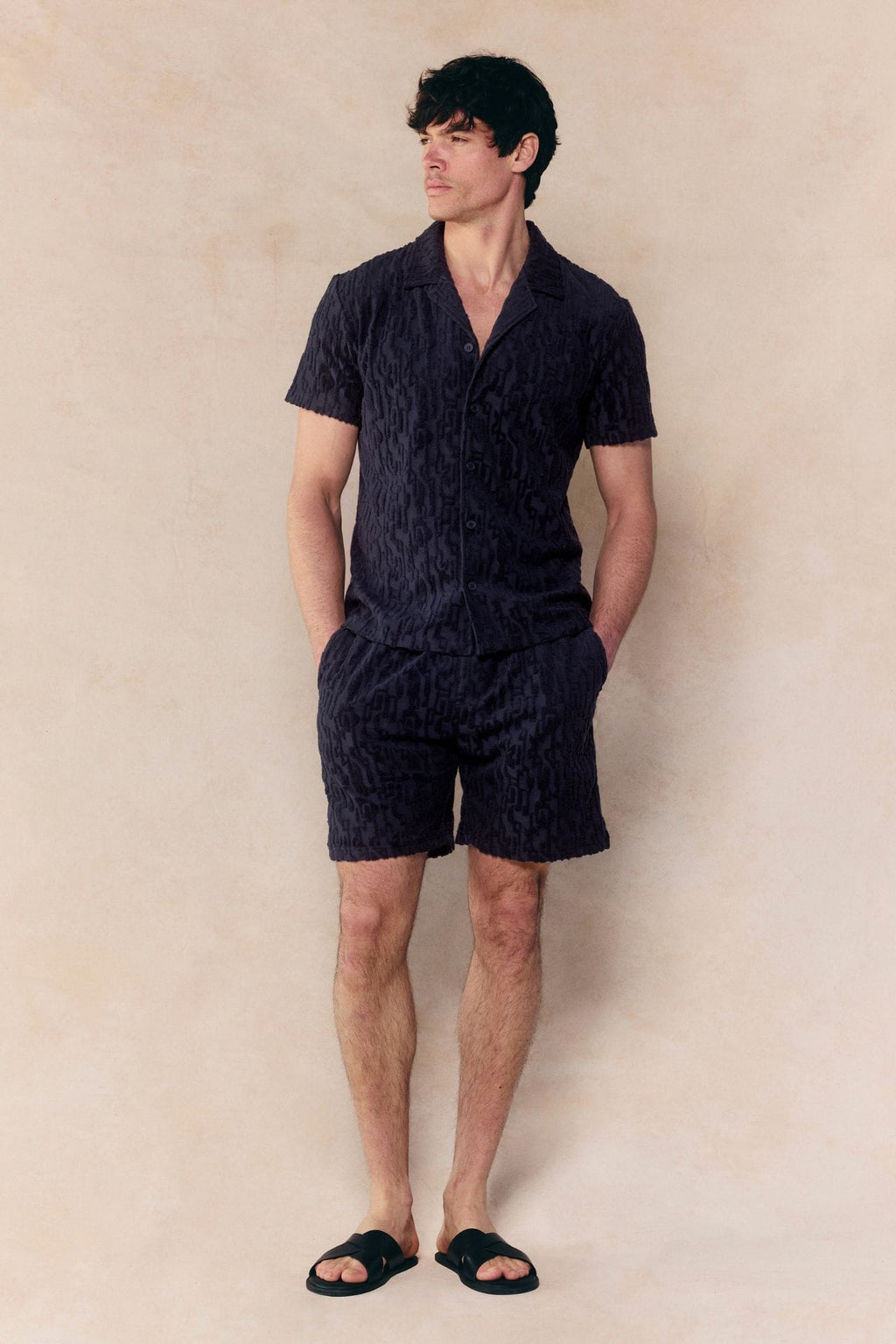 Man in navy Fausto Flocked Towelled Short and matching shirt, with a textured pattern.