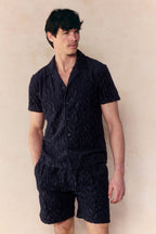 Man in navy Fausto flocked towelled short and matching short-sleeve shirt with textured pattern.