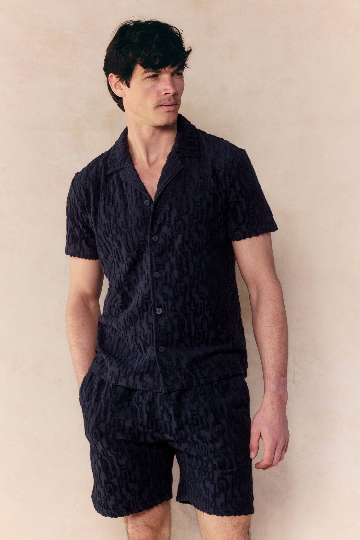 Man in navy Fausto flocked towelled short and matching short-sleeve shirt with textured pattern.
