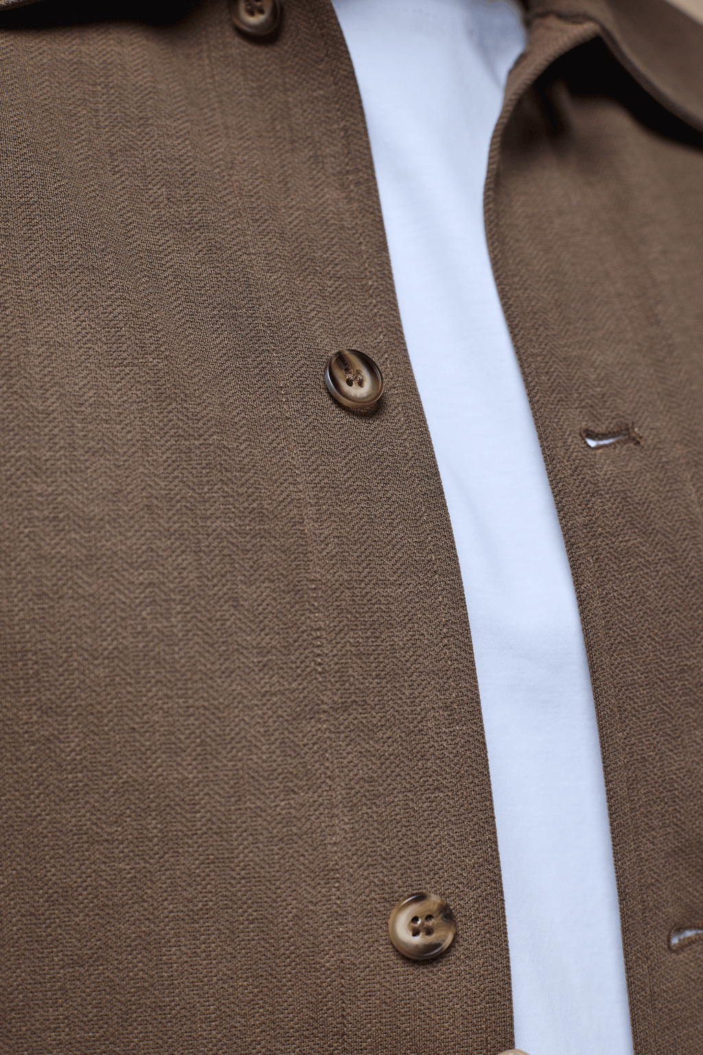 Close-up of a brown Geneva Textured Overshirt with faux horn buttons over a white t-shirt.