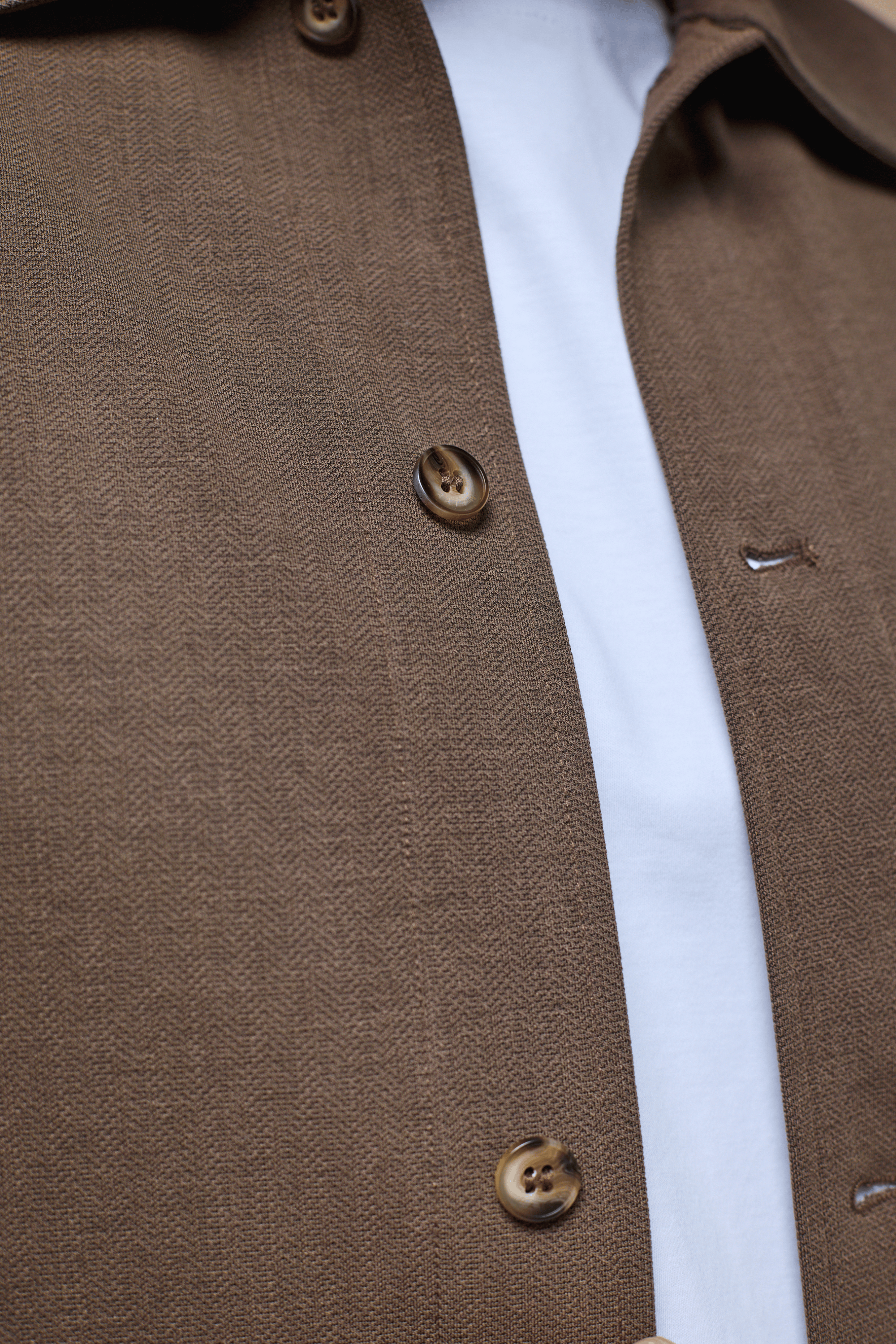 Close-up of a brown Geneva Textured Overshirt with faux horn buttons over a white t-shirt.