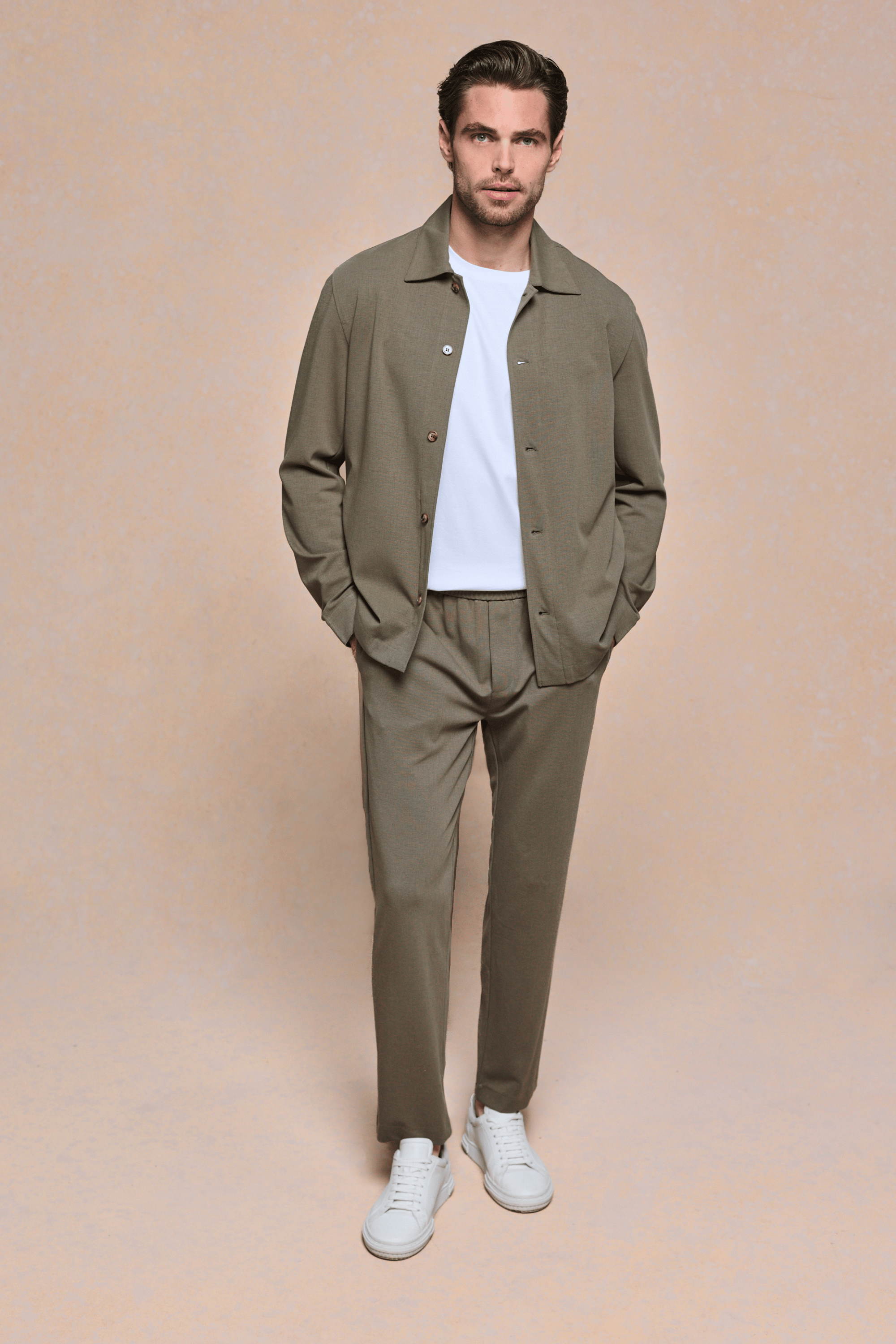 Man wearing a khaki Geneva textured overshirt and matching trousers with a white t-shirt and white sneakers.