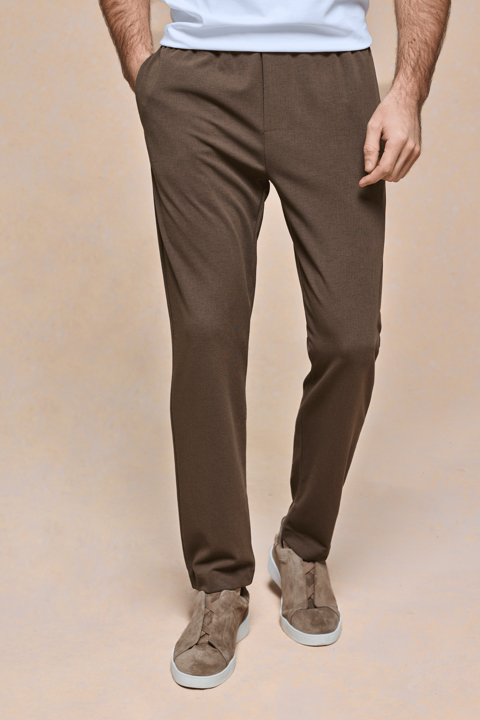 Men's brown textured tapered trousers with an elasticated waistband, side pockets, and a clean tailored fit.