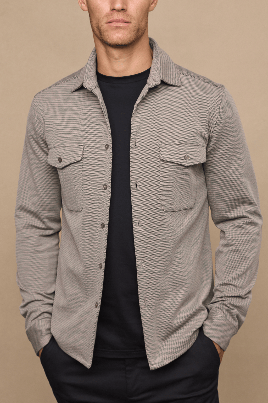 Man wearing a beige/brown textured overshirt with twin chest pockets over a black t-shirt.