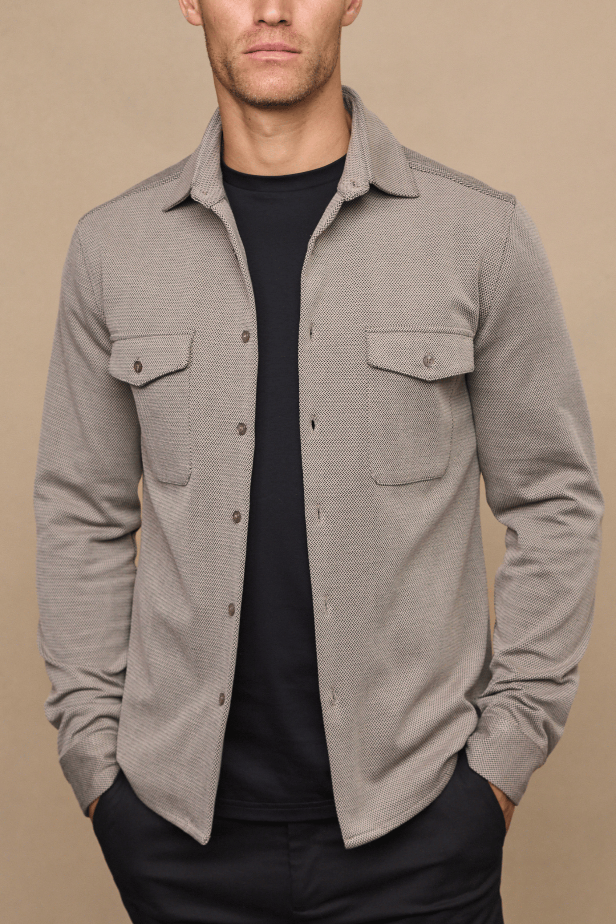 Man wearing a beige/brown textured overshirt with twin chest pockets over a black t-shirt.