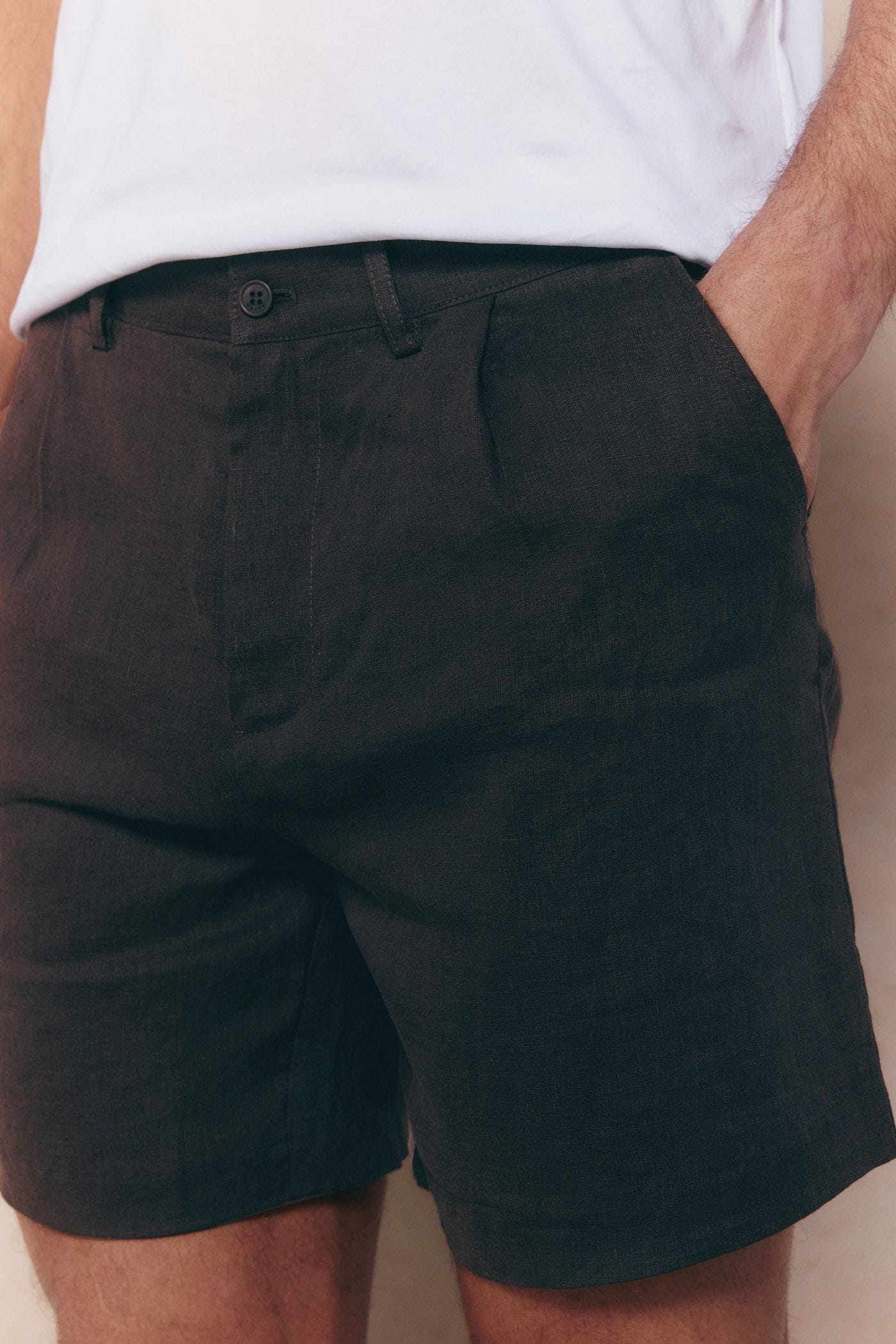 Close-up of brown Javier pleated waistband linen shorts with a front pleat and side pocket.