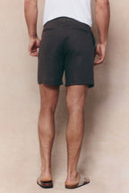 Man wearing brown Javier pleated waistband linen shorts with belt loops, seen from behind.