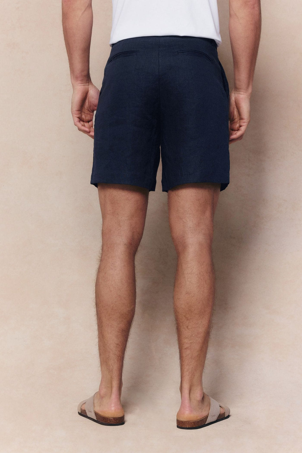 Man from behind wearing navy Javier pleated waistband linen shorts and sandals.
