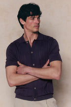 Man in navy Juan Button Thru Boucle Knit Striped Polo, short sleeves, full button-through front.