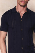 Man wearing a navy boucle knit striped polo with a full button-through front and short sleeves.