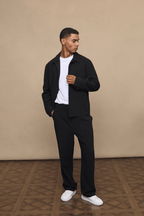 Man in black Julien Relaxed Panelled Trousers and matching jacket with a white t-shirt.