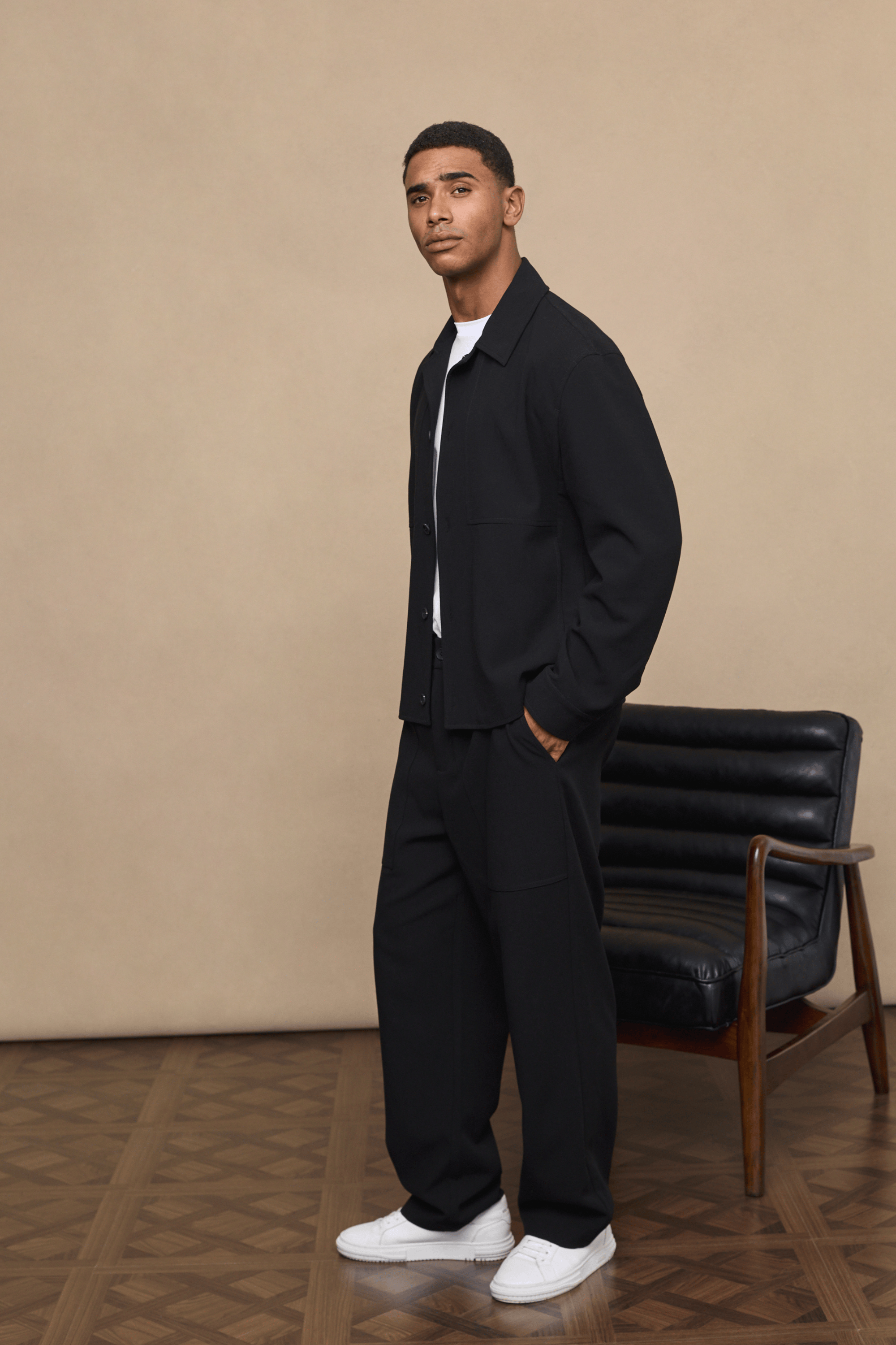 Man wearing black Julien relaxed panelled trousers and matching jacket with a white t-shirt.