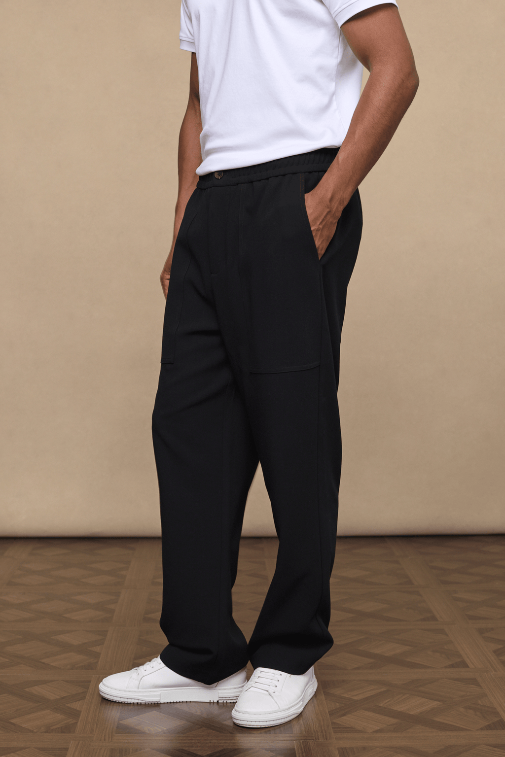 Man wearing black Julien Relaxed Panelled Trousers with a white t-shirt and white sneakers.