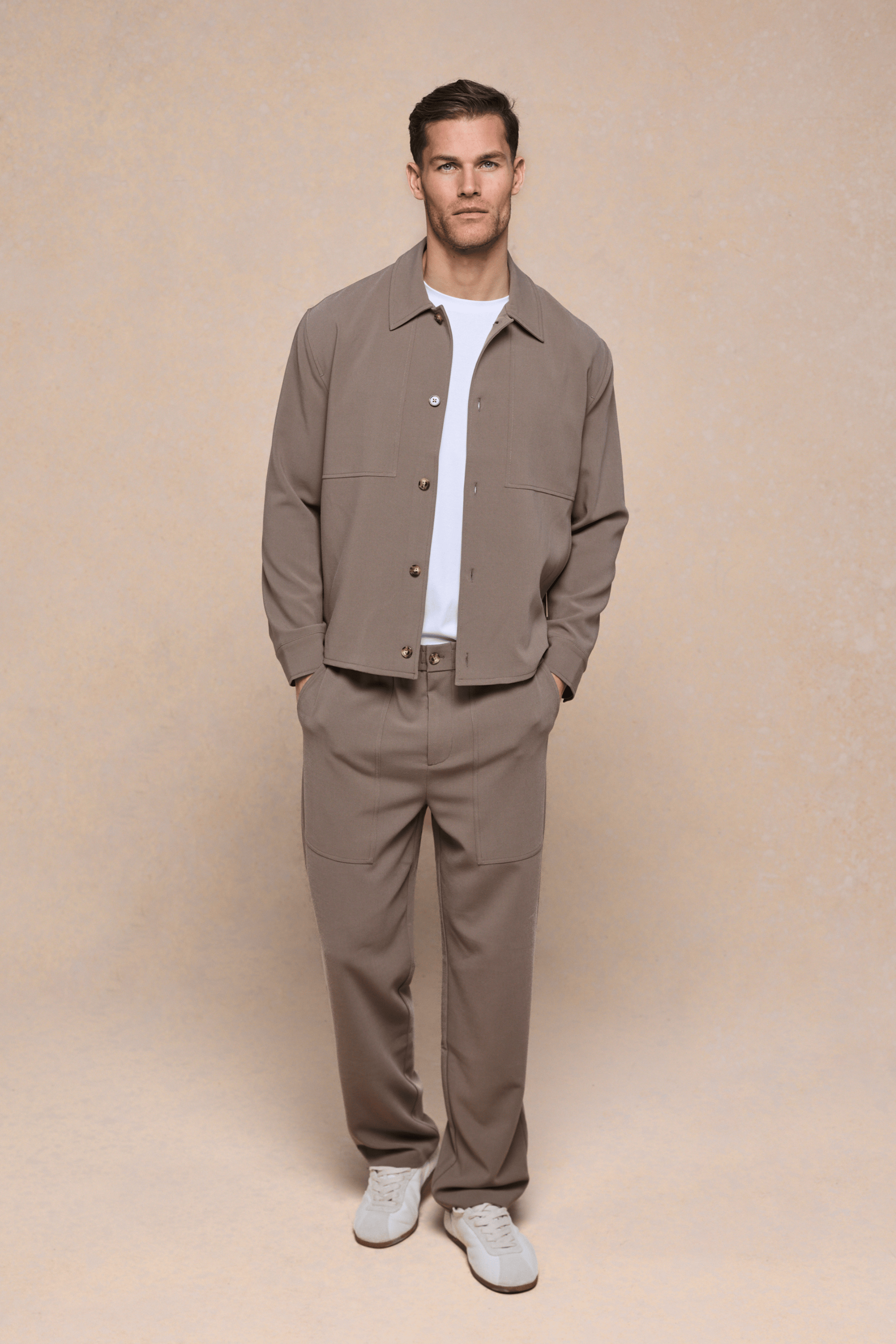 Man wearing olive Julien Relaxed Panelled Trousers and matching jacket with a white t-shirt.