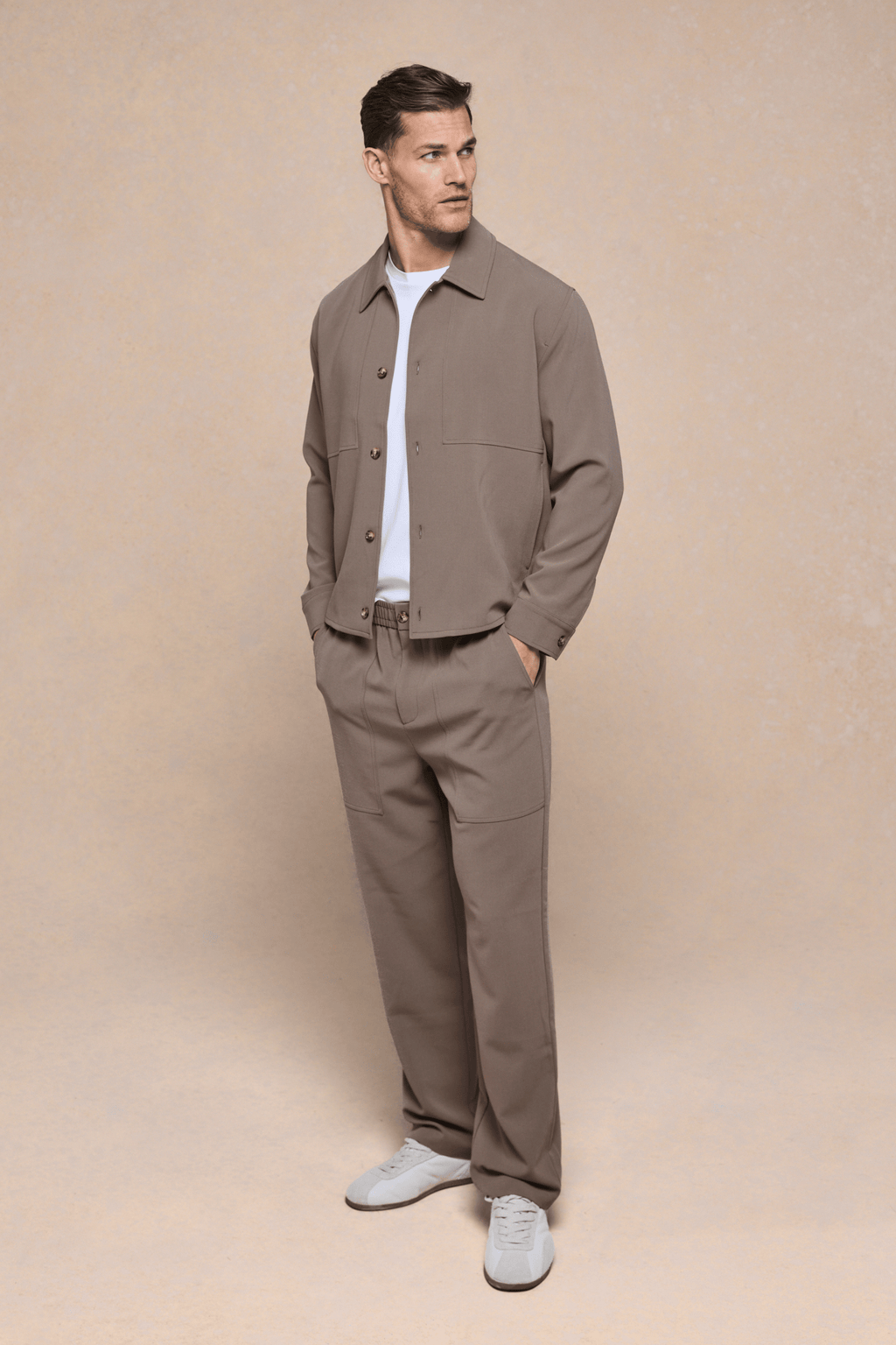 Man in olive Julien Relaxed Panelled Trouser and matching jacket, white t-shirt, and sneakers.